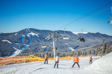 Karla kaplı bir dağın tepesinde kayak yapan bir grup insan.