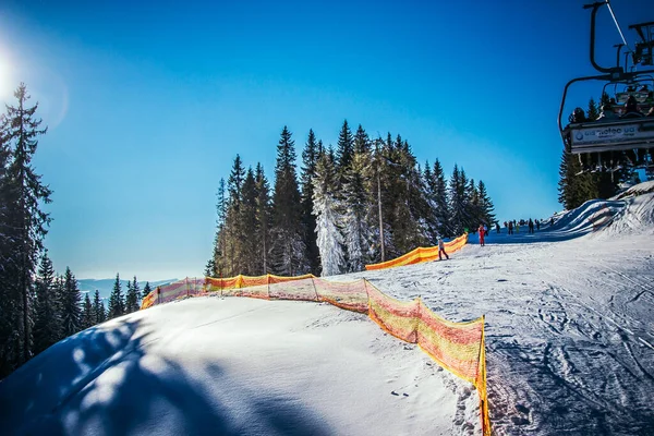 Um homem montando um snowboard para baixo uma inclinação coberta de neve — Fotografia de Stock
