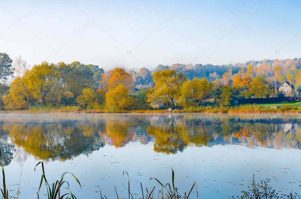 the lake is surrounded by autumn trees reflected in the mirror surface of the lake, quiet morning