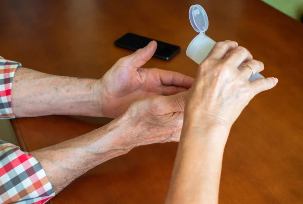 Senior couple using hand sanitizer gel at home after being on the street. Protection in older people against coronavirus.