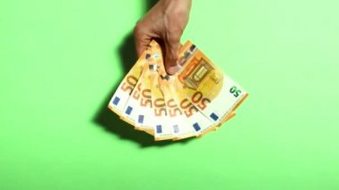 Yeşil arka planda 50 avroluk banknotların el ele tutuşması ve taşınması. Para kazanma, kumar, zafer, bahis...