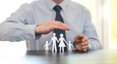 Sigortacı bir aileyi elleriyle koruyor.