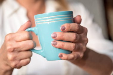 Kadının elinde bir fincan sıcak içecek tutarak yakın çekim