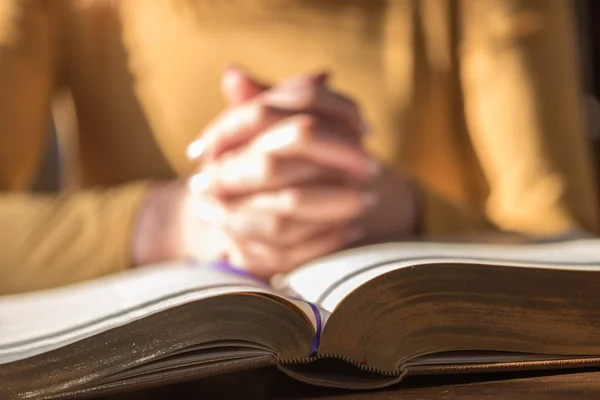 Acercamiento Mujer Rezando Con Sus Manos Sobre Biblia Luz Dura — Foto de Stock