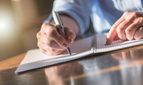 Woman with pen writing on notebook