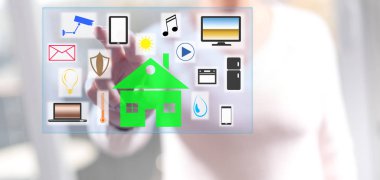 Kadın dokunmatik ekranda parmaklarıyla akıllı bir ev kavramına dokunuyor.
