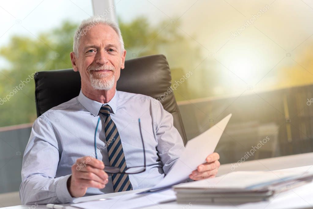 Portrait of mature businessman sitting in office, light effect