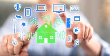 Kadın dokunmatik ekranda parmaklarıyla akıllı bir ev kavramına dokunuyor.