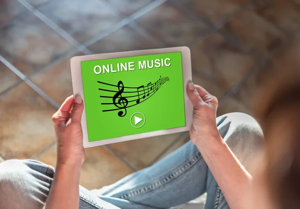 Bir tablet gösteren online müzik konsepti ile katta oturan kadın