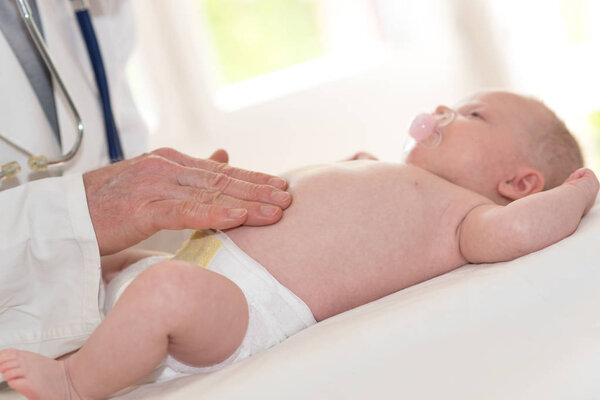 Врач-педиатр, осматривающий животик в клинике
