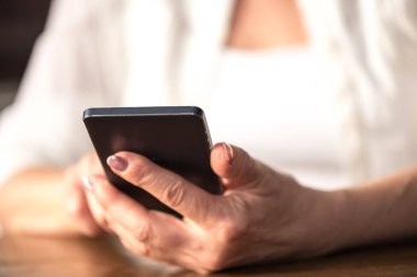 Kadının elinde bir cep telefonu kullanarak yakın çekim