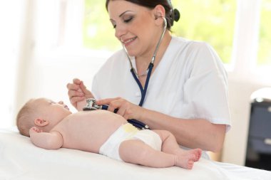 Küçük bir bebek incelemek için stetoskop kullanarak kadın çocuk doktoru