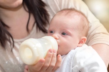 Anne bebeği süt şişesiyle besliyor.