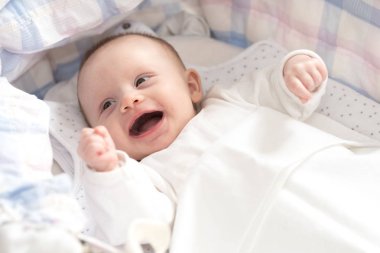Beşiğinde yatan sevimli gülen bebek kız portresi