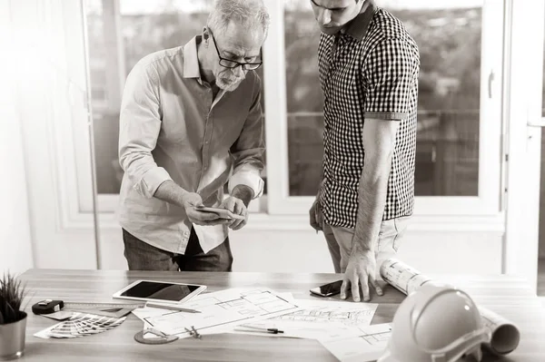 Architects working on plans at office, black and white