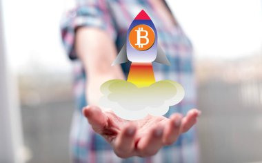 Bitcoin yükselişi kavramı arka planda bir kadının elini yukarıda