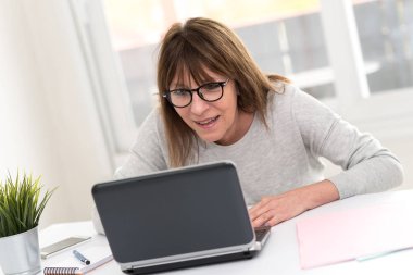 Şaşırtıcı bir sürpriz üstünde laptop sahip mutlu olgun kadın