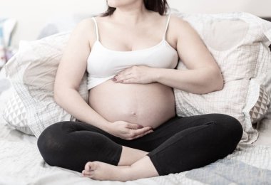 Karnında el ele tutuşan hamile bir kadın.