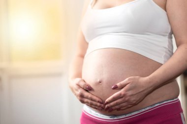 Karnında el ele tutuşan hamile bir kadın.