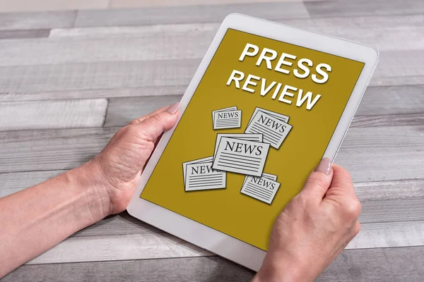 Female hands holding a tablet with press review concept