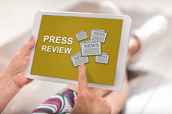 Woman using a tablet with press review concept