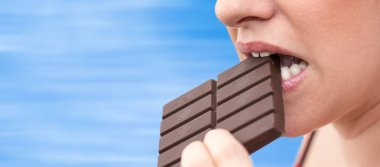 Kadının üzerinde arka plan bulanık bir çikolata ısırmak yakın çekim