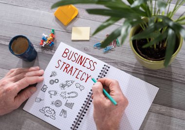 İş stratejisi kavramı üzerinde bir not defteri çizilmiş bir masa üzerine yerleştirilen