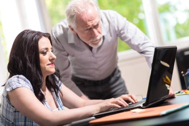 Genç iş kadını ve birlikte ofiste çalışan üst düzey iş adamı