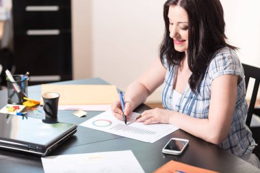 Genç iş kadını ofiste belgeler üzerinde çalışma