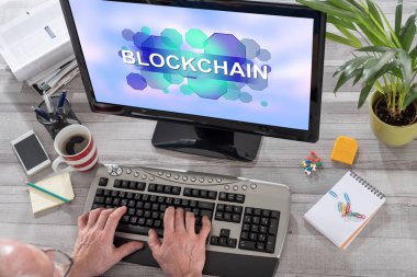 Blockchain konsepti üstünde belgili tanımlık perde ile bir bilgisayar kullanan adam