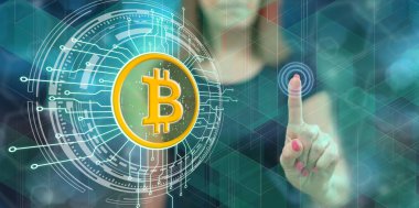 Kadın dokunmatik ekranda bitcoin para birimine dokunuyor.