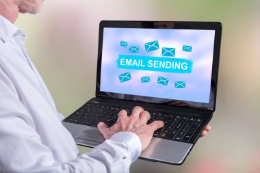 Ekranda e- posta gönderme konsepti olan bir dizüstü bilgisayar kullanan adam