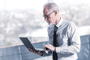 Ayakta ve onun dizüstü bilgisayarda çalışan bir üst düzey işadamı