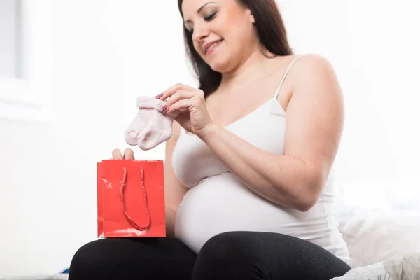 Šťastné těhotné ženy při pohledu na baby ponožky — Stock fotografie