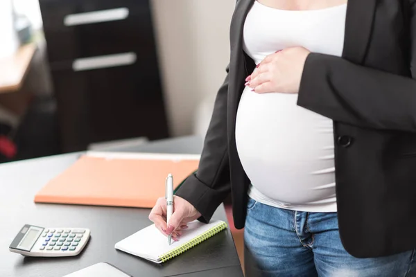 Έγκυος γυναίκα παίρνει σημειώσεις στο γραφείο — Φωτογραφία Αρχείου