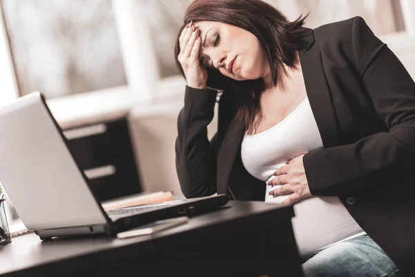 Těhotná žena v práci s bolestí hlavy — Stock fotografie