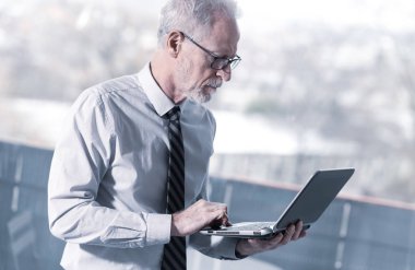 Ayakta ve onun dizüstü bilgisayarda çalışan bir üst düzey işadamı