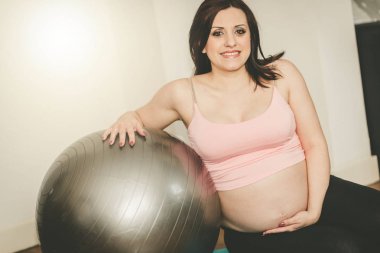 Hamile kadın inceliğine top, ışık etkisi ile oturuyor