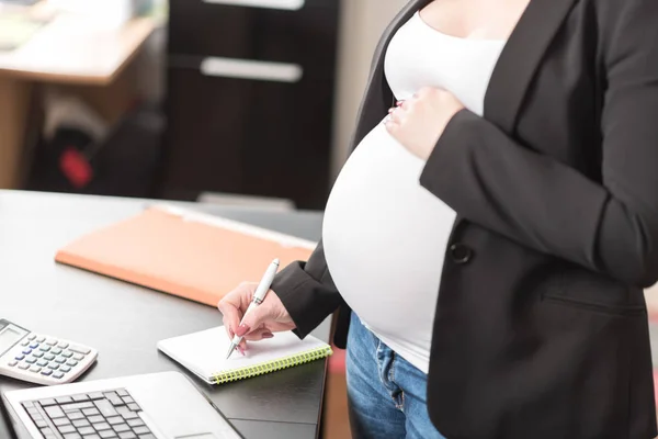 Těhotná žena zapisování poznámek v kanceláři — Stock fotografie