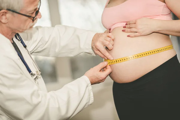 Лікар вимірює розмір живота вагітної жінки — стокове фото