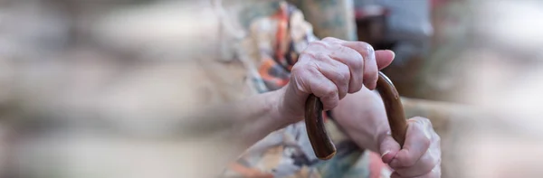 Alte Frau mit ihren Händen auf einem Stock. Panorama-Banner — Stockfoto