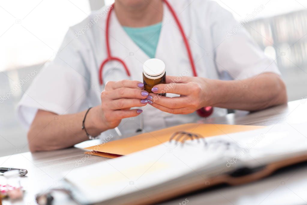 Female doctor looking at a bottle of pills