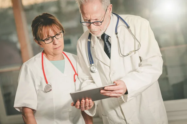 Due medici discutono del rapporto medico su tablet — Foto Stock