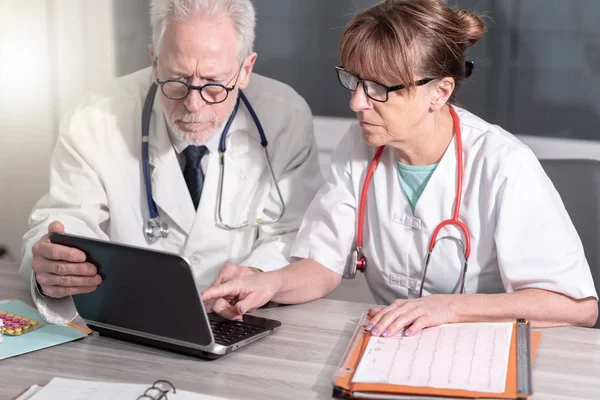 Due medici discutono di rapporto medico sul computer portatile — Foto Stock