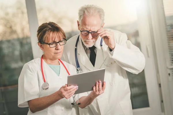 Due medici discutono del rapporto medico su tablet — Foto Stock
