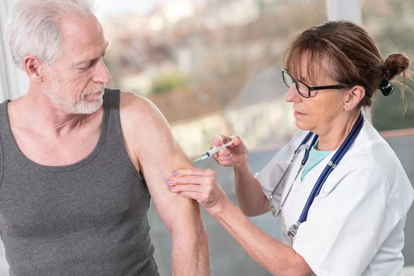 Vrouwelijke arts injecteren van vaccin aan senior patiënt — Stockfoto