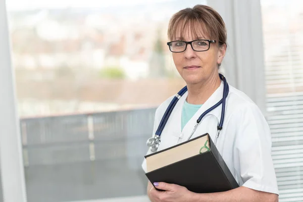 Médica feminina segurando um manual médico — Fotografia de Stock