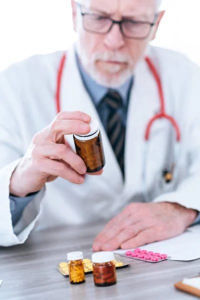 Lekarz patrząc na butelkę tabletek — Zdjęcie stockowe