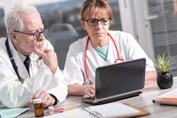 Zwei Ärzte diskutieren über ärztliches Gutachten am Laptop — Stockfoto