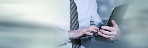 Senior om de afaceri în picioare și de lucru pe laptop; panoramic — Fotografie, imagine de stoc